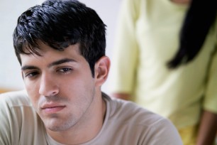 Unhappy young man with unknown woman in background, close-up, selective focus, focus on man